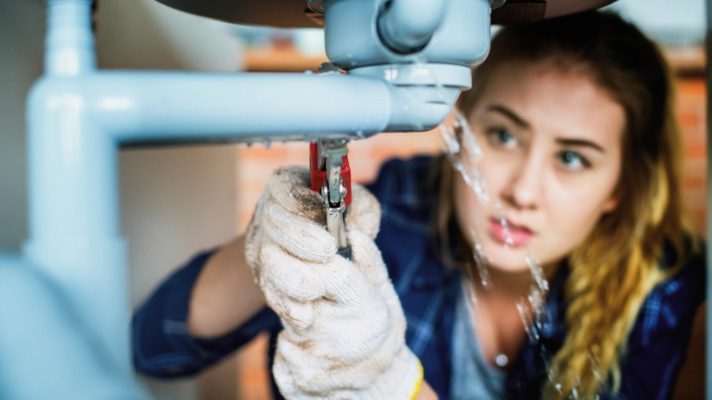 Female lpumber repairing a sink leak